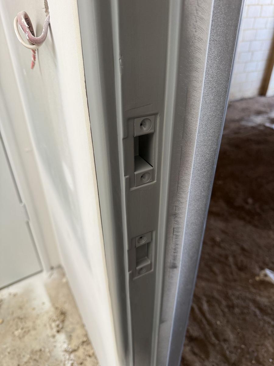 The same jamb ground smooth and primed, with the strikers fitted