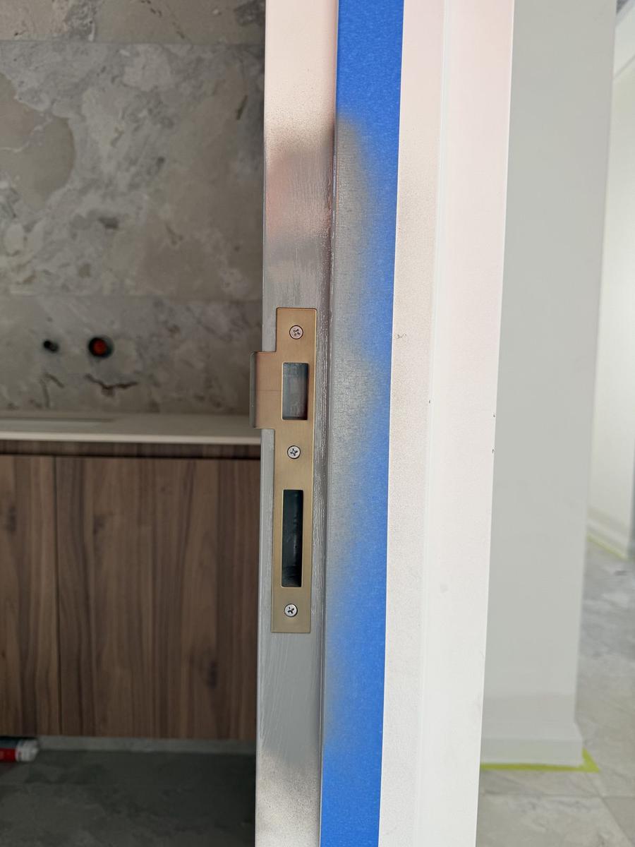 Lock striker fitted to a frame in a fitted-out interior