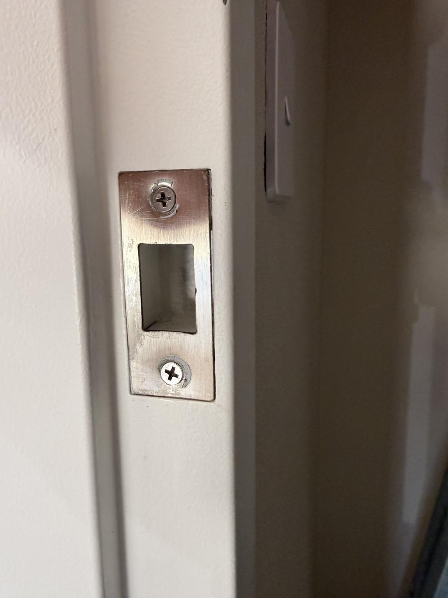 Stainless lock striker plate fitted to a door frame